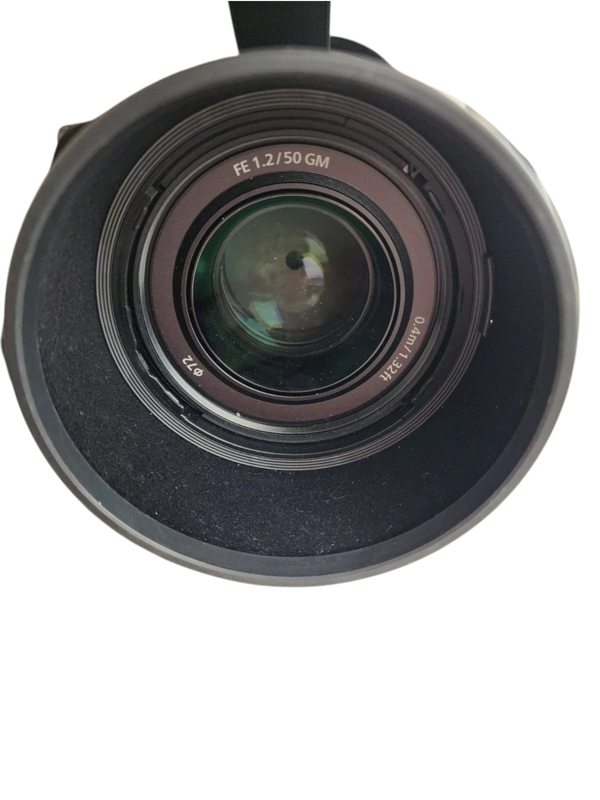 Cymer Sony FE 50mm f/1.2 GM lens with lens hood attached and lens cap resting on a marble surface