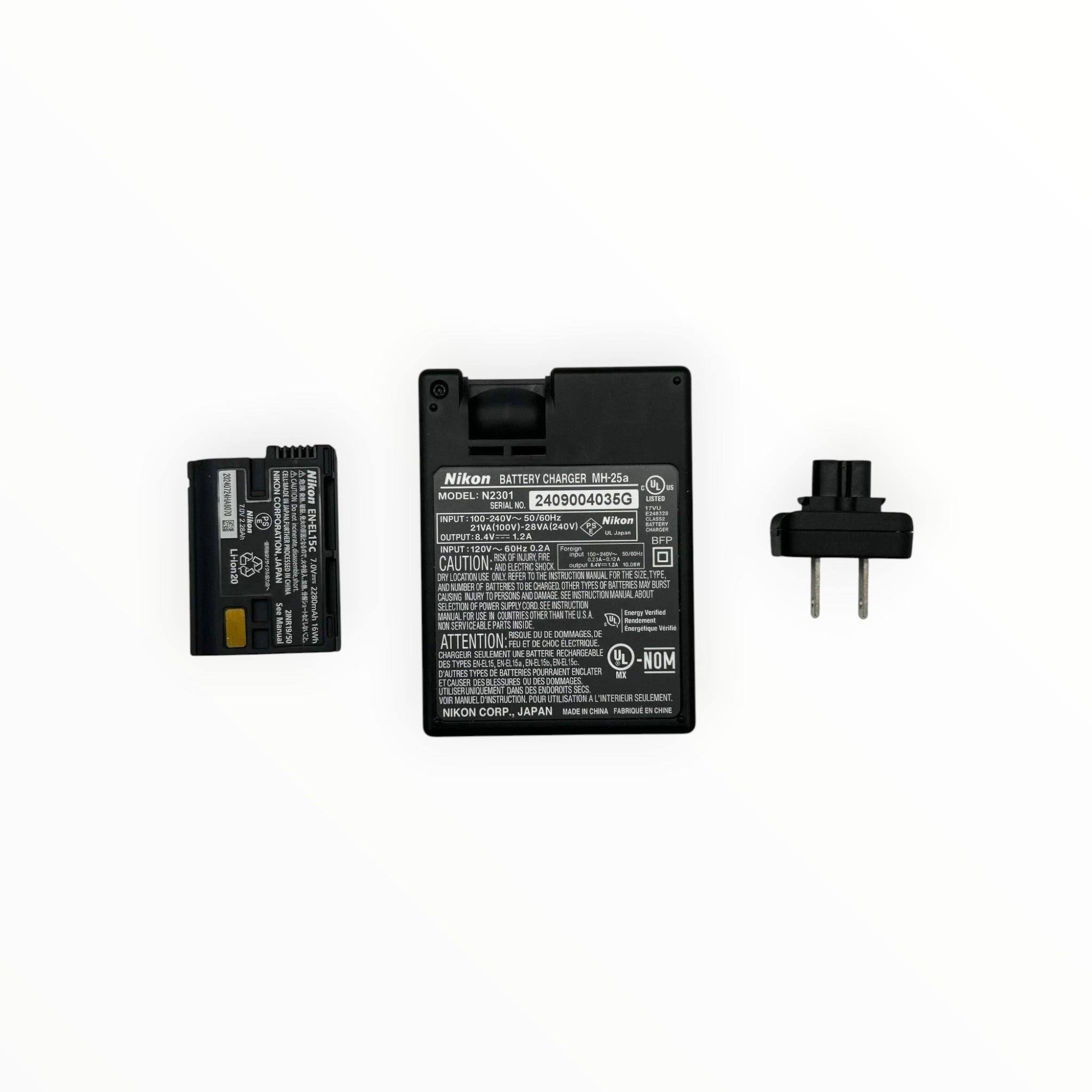Cymer Nikon EN-EL15c battery, MH-25a charger, and power plug on a white surface